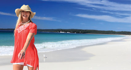 A smiling woman walking on a pristine beach