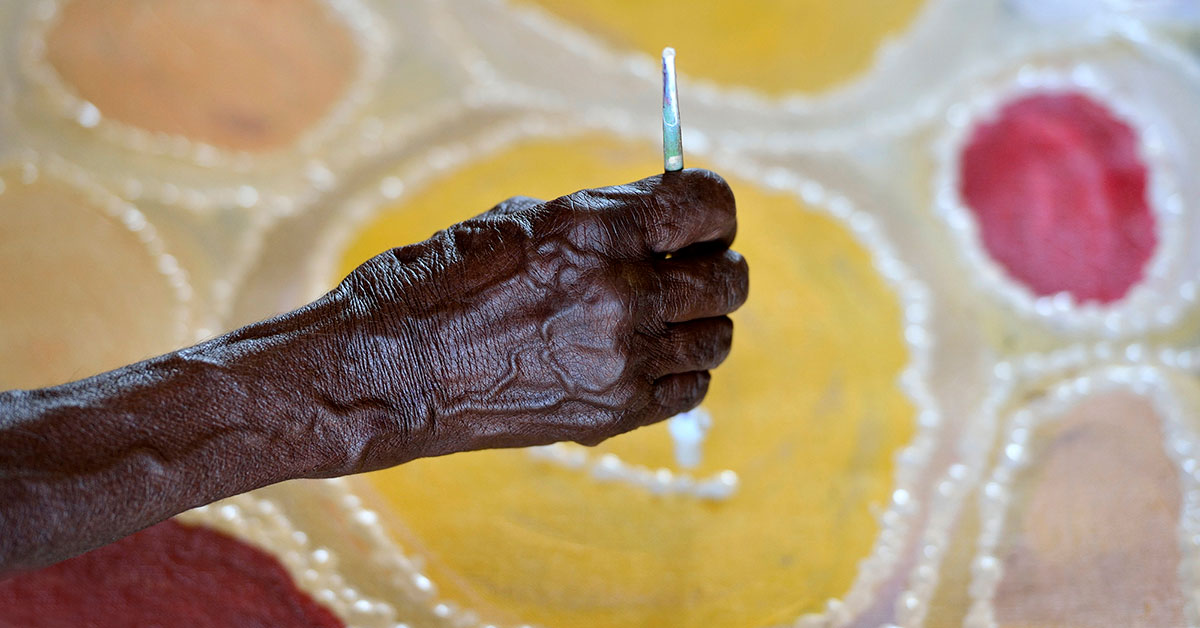 Aboriginal person's arm holding a paint brush.